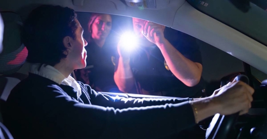 Police Officer Uses Flashlight While Talking to a Driver