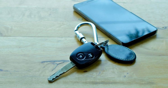 Car key and smartphone on wooden table