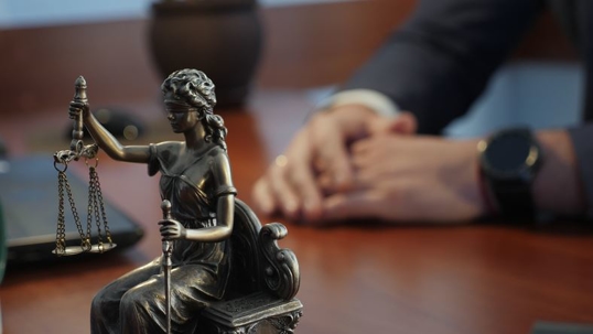 Lady Justice in foreground of lawyer's desk
