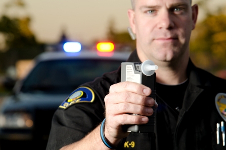 police officer holding breathalyzer